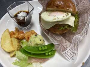 介護施設の食事。チーズバーガーと野菜、フライドポテトが白皿に盛られている。